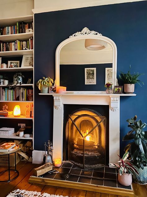 living room with fireplace, navy blue accent wall, white decorative trim, bookshelves Navy Fireplace Wall, Navy Fireplace, Small London Flat, Navy Accent Walls, Traditional Bedrooms, Dark Blue Living Room, Navy Living Rooms, Earthy Living Room, Long Living Room