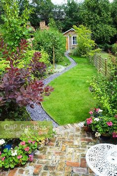 Elevated view of long, narrow town garden with lawn and sinuous path leading to garden studio. Brick paving, slate chippings, Cotinus, pots of Pelargoniums. Narrow Garden, Back Garden Design, Garden Design Layout, Garden Design Plans, Outdoor Gardens Design, Beautiful Flowers Garden, Backyard Garden Design, City Garden, Small Garden Design