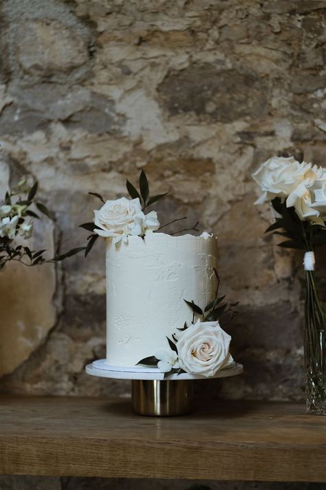 Single tier white frosted wedding cake with buttercream and decorated with white roses on white and gold cake stand Simple White Wedding Cake 1 Tier, White Roses On Wedding Cake, White Single Tier Wedding Cake, Stucco Wedding Cake, Single Tiered Wedding Cake, Textured White Cake, Plain White Wedding Cake, White Textured Wedding Cake, Button Back Wedding Dress