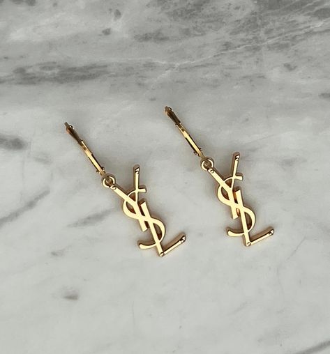 ✨ Beautiful reworked YSL Earrings & Necklaces are now back in stock! ✨ Get yours now before they’re gone again! ✨ Repurposed from authentic pre-loved YSL necklace charms and handcrafted in Melbourne with love 🫶🏼 ✨ Free shipping Australia wide. #yvessaintlaurent #yvessaintlaurentjewellery #repurposedjewelry #vintagejewels #vintageaesthetic #goldjewellery #sustainablejewelry #saintlaurent #prelovedysl #aestheticphotography #vintageysl #reworkedvintage #designerjewelry #ysl #upcycledjewelry #v... Gold Earring Aesthetic, Branded Earrings, Luxury Must Haves, Ysl Accessories, Ysl Bracelet, Ysl Earrings, Saint Laurent Earrings, Ysl Necklace, Ysl Jewelry