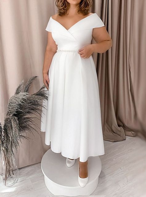 This timeless off-the-shoulder satin A-line dress is designed with a natural waistline and Tea Length hemline for an elegant romantic look. Enchanting details include a delicate lace-up back and chic belt embellishments, making it the perfect dress for any season. Midi Wedding Dress Plus Size, Short Off The Shoulder Wedding Dress, Minimalist Wedding Dress Plus Size, Civil Wedding Dresses Plus Size, Wedding Dresses For Plus Size Women, Plus Size Short Wedding Dresses, Short Plus Size Wedding Dresses, Plus Size Short Wedding Dress, Short Wedding Dress Plus Size