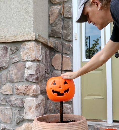 What says fall more than pumpkins? Here is a super easy and inexpensive way to dress up your porch for fall.    Step 1: Get pumpkins  Run, do not walk, to Walmart where plastic pumpkin pails are only $1.00 while supplies last. For one planter, purchase 5 pumpkins.    Step 2: Rebar  Purchase 4' rebar rods and place them into a pot (yellow circles). Secure with stones and soil. I made two planters so I purchased 2 rebar rods and 10 pumpkins.    Step 3: Cut the Handles  We don't need the… Stacked Pumpkins In Planter, Pumpkin In Flower Pot, Fence Post Pumpkins Diy, Plastic Pumpkin Tower Diy, Pumpkin Porch Decorations Diy, Fall Porch Pots With Pumpkins, Walmart Pumpkin Crafts, Pumpkin Outside Decor, Pumpkin Bucket Planter