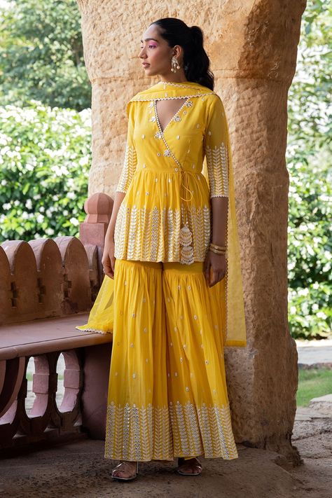 Buy Yellow Peplum Top Cotton Mulmul Leaf Angrakha Sharara Set For Women by PREEVIN Online at Aza Fashions. Angrakha Style Kurti With Sharara, Angrakha Peplum Top, Beautiful Sharara Designs, Sarara Design Latest, Peplum Top Outfits Indian, Peplum Sharara Suit, Haldi Dress Ideas For Sisters, Haldi Dresses, Peplum Sharara