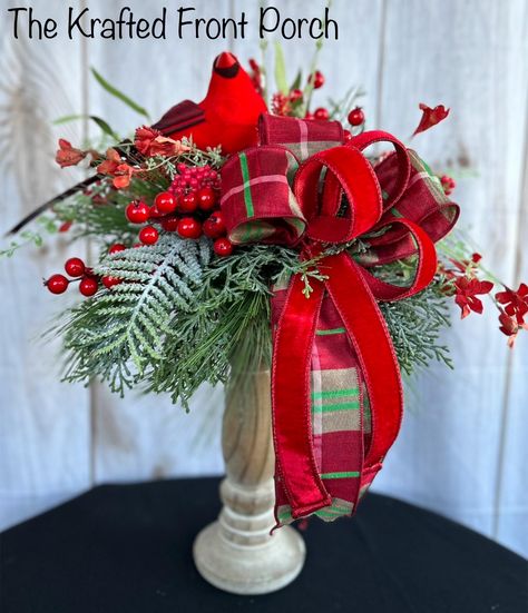 Bring the beauty of nature into your home this holiday season with this handcrafted Christmas floral arrangement featuring a charming red cardinal perched among lush evergreen branches, bright red berries, and a festive plaid and velvet ribbon. Nestled in a rustic wooden base, this arrangement is perfect for a mantelpiece, table centerpiece, or a holiday gift for loved ones. Its timeless design captures the spirit of winter and adds a cheerful touch to any décor. Order now to make your holiday season more special! Christmas Pedestal Decor, Christmas Silk Arrangements, Red Vases With Flowers, Candle Stick Christmas Centerpiece, Centerpiece Christmas Table Diy, Holiday Candle Ideas, Large Christmas Centerpieces, Christmas Topiaries, Christmas Candlestick Arrangements