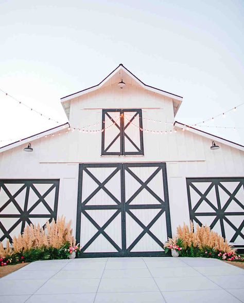 A Boho California Wedding with a Tropical Twist | Martha Stewart Weddings - Following dinner, guests were led to the side of the property, where a white barn with black trim anchored the dancing space, and the same floral arrangements that framed the ceremony were repurposed to the sides of the barn's doors. White Shop With Black Trim, Black And White Barn Wedding, Barn Exterior, Wedding Locations California, Black Barn, Party Barn, Tropical Twist, Dinner Guests, Wedding Barn