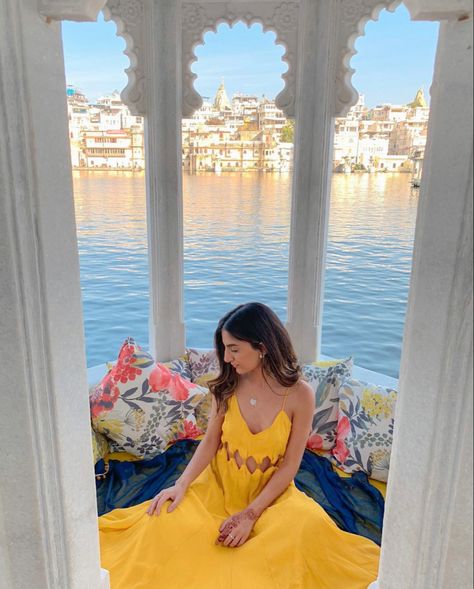 Girl wearing yellow maxi sitting under intricate stone detailed arch way with lake pichola in the background in udaipur Udaipur Photography Lakes, India Outfits Travel Summer, Outfits For Udaipur Trip Women, Photoshoot In Udaipur, Rajasthan Travel Outfit Ideas, Lake Pichola Udaipur Photography, India Photoshoot Ideas, Udaipur Picture Ideas, Poses In Rajasthan