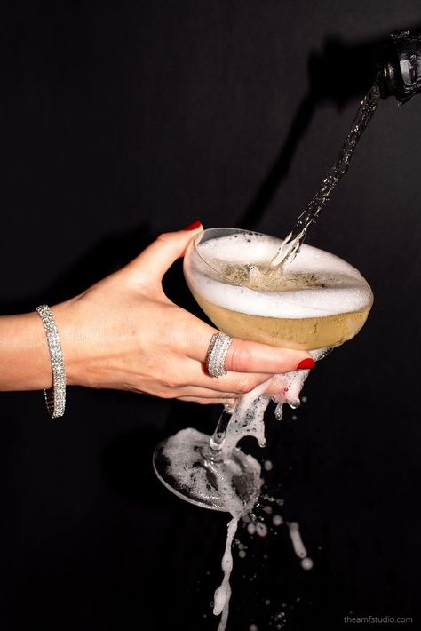 Woman's hand holding a wide champagne glass wearing a diamond tennis bracelet and ring while there's champagne overflowing the glass against a black background. New Years Jewelry Photography, Jewelry Editorial Photography Still Life, Champagne Still Life, Diamond Jewelry Photoshoot, Jewelry Marketing Ideas, Christmas Beauty Photography, Lifestyle Jewelry Photography, Holiday Jewelry Photography, Christmas Jewellery Photography