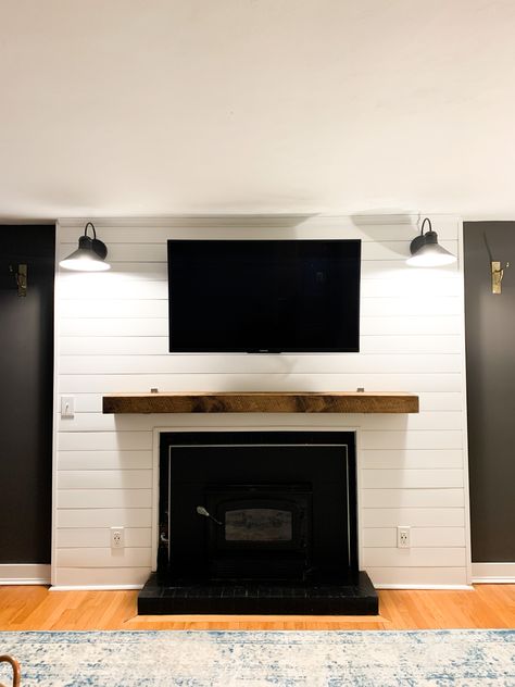 Shiplap, wood beam as mantle, Wood stove insert, sconce lighting, outlets, accent wall Fireplace Tv Wall With Sconces, Wood Stove With Mantle And Tv, Shiplap Wall With Sconces, Tv Wall Design Shiplap, Accent Wall With Mantle, Mantle Wood Stove, Shiplap Accent Wall Living Room With Tv, Fireplace Mantle Shiplap, Shiplap Tv Accent Wall