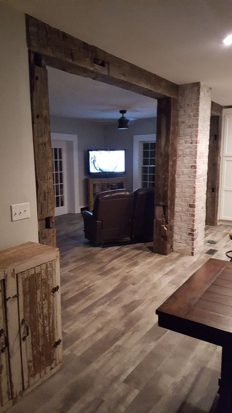 Take a look at these reclaimed wood beams used to frame the walkway between the kitchen and living room in this home. What a unique touch! Cedar Beams Living Room, Archway Between Kitchen And Living Room, Beam Between Kitchen And Living Room, Maine Kitchen, Modern Cabin Interior, Beams Living Room, Reclaimed Beams, Brick Columns, Reclaimed Wood Beams