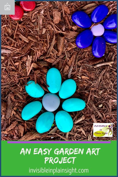 River rocks and acrylic paint are all you need to create these whimsical brightly colored flowers for a no-maintenance garden. Painted Rock Flower Garden, Painted Flower Rocks Garden Art, Flower Rock Garden, Painted Rock Flowers In Garden, Rock Flowers In Garden Stone Art, Painted River Rocks Garden, Painted Rock Landscaping Ideas, Painted Stones Flowers, Rock Flowers In Garden