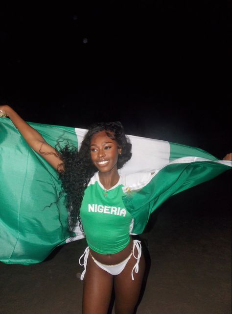 a black girl in a ‘nigeria’ baby tee carrying the nigerian flag on a beach at night Nigeria Aesthetic, Nigerian Independence