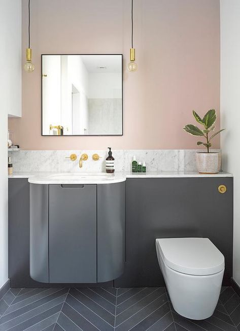 A dark gray curved bath vanity topped with quartz countertops against a pink bathroom wall lit by black and gold hanging Edison bulb lights. Bathroom Colors Blue, Pink Bathroom Tiles, Peach Bathroom, Pink Bedroom Walls, Industrial Style Bathroom, Grey Countertops, Bathroom Modern, Bathroom Backsplash, Pink Bathroom