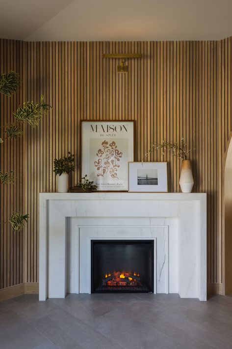 Upon entering the NoHo residence, you'll be greeted with a breathtaking marble fireplace against a custom slatted wall. Wood Panel Fireplace Wall, Entry Fireplace, Studios Interior Design, Slatted Wall, Wood Fireplace Surrounds, Basement Living, Basement Living Rooms, Wood Slat Wall, Marble Fireplace