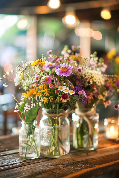 Discover the perfect blend of simplicity and elegance for your big day! 🌼💐 Our DIY wedding centerpieces feature vintage mason jars, handpicked wildflowers, and natural twine accents. Create a cozy, romantic atmosphere at your reception. #WeddingInspiration #RusticWedding #DIYBride #MasonJarDecor #WildflowerCenterpieces #VintageWeddings #SimpleElegance #RomanticDecor Wedding Flower Vases Reception Ideas, Jar Wedding Decor, Wildflower Table Arrangements, Wild Flowers In Mason Jars, Wedding Flowers Summer Simple, April Centerpiece Ideas, Diy Center Piece Ideas, Simple Wildflower Centerpieces, Wildflower Mason Jar Centerpieces