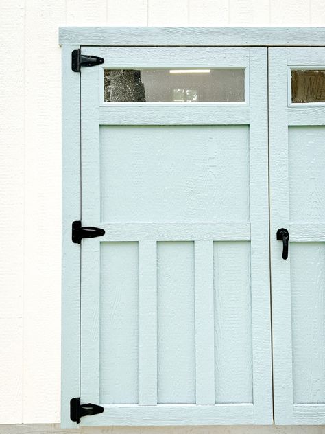 Come see how I took this boring shed and painted the exterior to freshen it up! I’m obsessed with how the white paint looks against the blue doors - it’s exactly what this workshop needed! Click here to go to withlovemercedes.com to see paint colors and how I did it! #shed #shedmakeover #exteriorcolors #sheshed #tuffshed #paintcolors #exteriorpainting #howtopaint #bluedoor Shed Blue Door, Shed Door Colors, Shed Paint Colours, Prefab Sheds, Shed Makeover, Tuff Shed, Shed Door, Blue Doors, Shed Doors