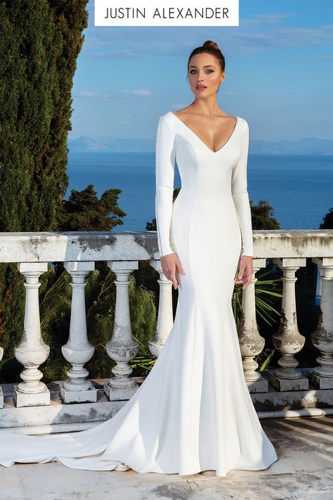 All eyes will be on you in this crepe long sleeve gown. It features a pearl seam detail down the sleeves, along the wrists and at the neckline. A clean V-back with pearl buttons down the train create this stunning wedding day look. This style is also available without the pearls along the sleeves. Long Sleeved Wedding Dress, Justin Alexander Bridal, Sleeved Wedding Dress, Justin Alexander Wedding Dress, Plain Wedding Dress, Long Sleeve Wedding Gowns, Sleeved Wedding, Trumpet Wedding Dress, Justin Alexander