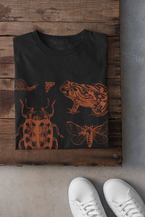 Thanks for stopping by! Cottagecore Snails, Frogs and Bugs T-shirt Printed on a super soft, cotton tee Dispatched in 5 working days or sooner Unisex Free UK delivery Material: 100% ringspun cotton. Chest (to fit): S  34/36   M  38   L  40/42   XL  44/46   XXL  48/50 ECO-FRIENDLY Each garment is made to order, reducing extra material and energy that would be otherwise wasted We use DTG printing process which is easier on the environment than screen-printing Our ink is bright and also eco-friendly Bleach Bug Shirt, Goth Cottagecore Aesthetic, Insect Shirt, Bleach Tshirt, Frog Tshirt, Fairycore Clothing, Bleach T Shirt, Bleach Shirt Diy, Bleaching Clothes