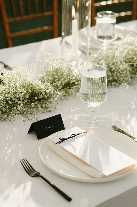 modern minimal wedding place setting babies breath floral runner black accents Wedding Table Place Settings Elegant, White And Black Place Settings, Black Plates Table Setting Wedding Ideas, All White Wedding Place Setting, Minimalist Place Setting Wedding, Babys Breath Wedding Ideas, All White Wedding Tablescape, Minimal Tablescape Wedding, Formal Wedding Place Settings