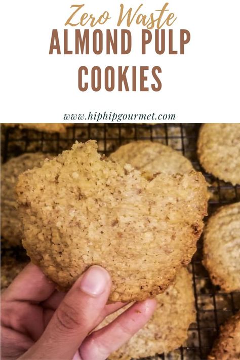 hand holding up one almond pulp cookie over a dozen more cookies on a wire rack Leftover Almond Pulp, Almond Pulp Bread Recipes, Nut Pulp Cookies, Oat Pulp Cookies, Leftover Almond Pulp Recipes, Almond Milk Cookies, Walnut Pulp Recipes, Almond Milk Pulp Recipes, Nut Milk Pulp Recipes