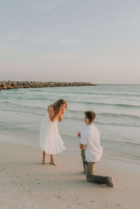 Young couple dressed in white & neutral summer clothing - on shore of beach in St Andrews State Park, PCB Florida.  Young man is kneeled down on one knee, with ring outstretched, girl is excitedly covering her face with her hands. Photo taken by intimate wedding & portrait photographer Brittney Stanley of Be Seen Photos Beach Engagement Surprise, Simple Proposal Ideas Beach, Wedding Rings Beach, Surprise Beach Engagement, Engagement At The Beach, Proposal Beach Photos, Engagement Photos Surprise, Surprise Beach Proposal, Engagement On Beach