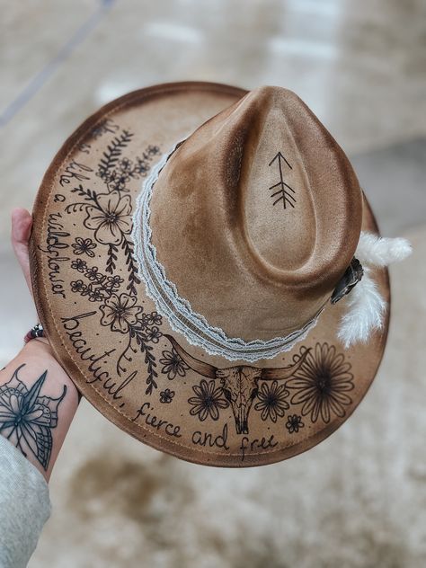 This is a tan suede hat with flowers, words, and a longhorn skull burned in.  Comes with everything you see on the hat as well.  This hat is adjustable and fits MOST head sizes.  Keep in mind each hat is free hand burned so can differ slightly. Lainey Wilson Hats, Hat Burning, Custom Cowboy Hats, Lainey Wilson, Longhorn Skull, Suede Hat, Hand Burn, Painted Hats, Boho Hat