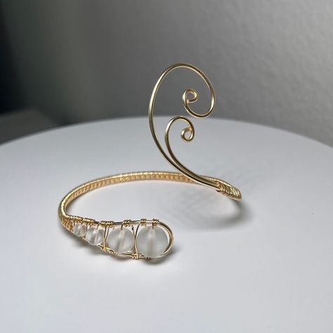 ✨This simple yet stylish wrist cuff is a must-have accessory for any fashion-forward individual. This cuff is made with glass beads and gold colored jewelry wire, which gives it a unique and elegant look. The asymmetrical design with swirl adds a touch of sophistication to the cuff, making it stand out from other wrist cuffs.   This cuff is adjustable, which means it can fit comfortably on any wrist size. This feature makes it a versatile accessory that can be worn by anyone, regardless of their Mermaid Trinkets, Colored Jewelry, Strawberry Moon, Swirly Designs, Wire Wrapped Stone Jewelry, Santa Margarita, Plant Jewelry, Wire Jewelry Designs, Diy Wire Jewelry