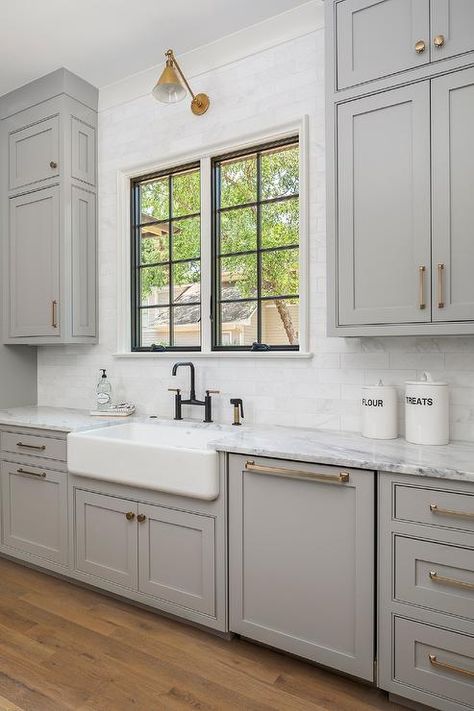 Oil rubbed bronze hardware on light gray cabinets in a transitional kitchen fitted with a farmhouse sink under a window surrounded by white brick stacked backsplash tiles. Kitchen With Gray Cabinets, Pike Properties, Natural Floors, Future Farmhouse, Light Grey Kitchen Cabinets, Light Grey Kitchens, Light Gray Cabinets, Grey Kitchen Designs, Marble Sink