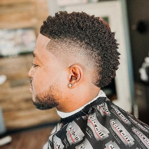 This hairstyle features a Burst Fade on the sides and a Faux Hawk on top. Fauxhawk Fade Men Faux Hawk, Black Hair Mohawk, Haircut For Black Men, Faux Hawk Haircut, Fade Faux Hawk, Black Mohawk Hairstyles, Faux Hawk Men, Hawk Haircut, Mohawk Fade