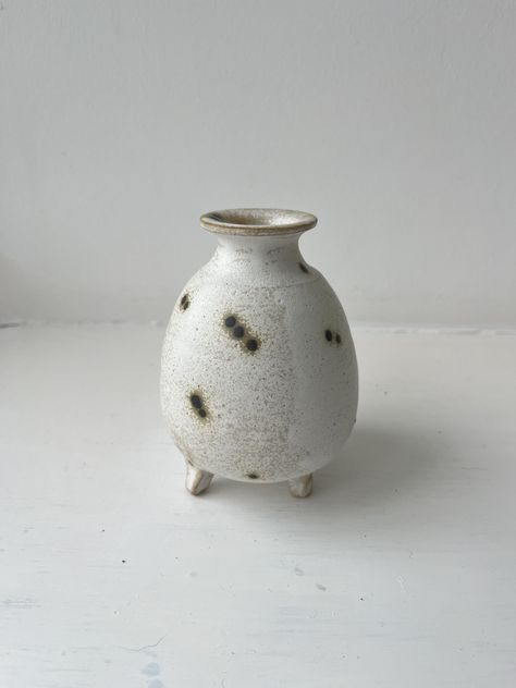 This is a handmade stoneware ceramic footed budvase candle holder/candlestick. It has a mat white glaze with small black spots. It is made from stoneware speckled clay. The three little feet is my signature detail. Dimensions: Height:  10.5 cm Width: 7 cm Opening diam: 2cm My danish background is very prominent in my ceramics. A sense of white and silverbirch is reflected in my designs. All pottery is designed and handmade by me. Simple minimal designs with their own unique charm and character. Danish Background, Small Vase Pottery, Bud Vase Ceramic Pottery, Tiny Ceramic Vases, Cermaic Bud Vase, Circular Art, Speckled Clay, Artisan Vase White, White Vase