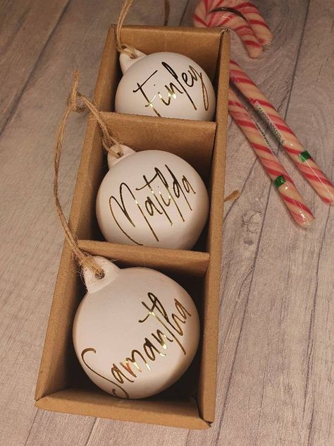 Personalised Christmas Baubles - This is the signature design - others are available on my other listings These are our gorgeous white ceramic baubles that are perfect to hang from your tree or to add around the house . Each bauble has a rustic matte white ceramic finish with a length of jute hanging string and can personalised with either metallic gold, metallic silver, black or red text. The text is written in our signature font. Add the names of your friends and family and give as gifts or de Bauble Gift Ideas, Personalised Ceramic Baubles, Cricut Bauble Ideas, Ceramic Baubles Christmas, Cricut Xmas Gift Ideas, Christmas Vinyl Projects To Sell, Cricut Christmas Projects To Sell, Custom Baubles, Cricut Christmas Gifts