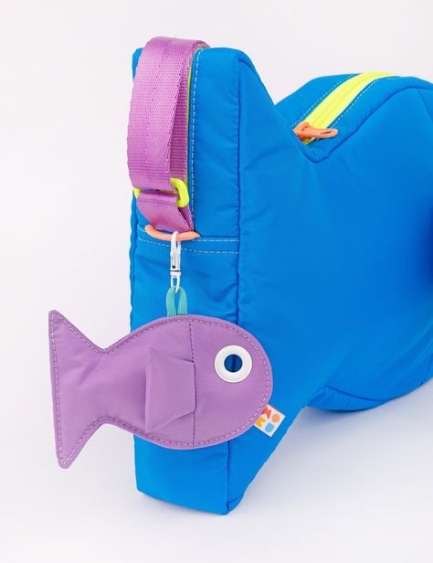 Find a new friend in this super plushy Fish Purse! This bag is so comfy and soft to wear, you'll be making it your daily driver. The inside is super roomy and can fit everything you need. Store small items in the two inside pockets. The grommet eye is the perfect size to thread your phone charger through to keep your phone charged and on hand! Hang your keys or our matching Fish Keychains off the double zipper pulls or the paracord loops on the head & tail of the bag. Adjust the strap to your perfect length- swim along with your shoulder bag or cross body style. Shop The Fish Collection Water resistant 100% nylon fabricFully lined Strap adjusts from 32" to 60" 9.5" tall x 12.5" wide x 2.5" deep, 9 oz. Capacity- 4.8 L Made in Los Angeles, California Keychain Sewing Pattern, Fish Keychains, Fish Purse, Fish Keychain, Fish Bag, Plush Design, Saltwater Fish, Bicycle Bag, Fish In A Bag