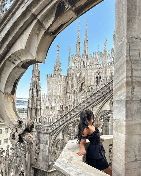 A girl in a black off the shoulder dress, with her long black hair in a half up hairdo, leans on the railing, looking off at the scenery behind her, which showcases the cathedral’s vast detail high in the sky, built of stone in tones of creamy white, sand pink, and streaks of marbled gray. Milan Travel Outfits, Summer Outfits Milan, Milano Outfit Ideas, Europe Trip Picture Ideas, Milan Spring Outfit, Milan Photoshoot Ideas, Photo Ideas In Italy, Milan Italy Outfit Summer, Duomo Di Milano Photo Ideas