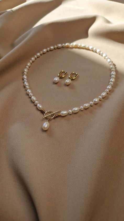 Elevate her neckline with our stunning natural pearl jewelry set. This gorgeous freshwater pearl toggle necklace adorned with a single radiant pearl, symbolizes purity and elegance. The toggle design adds a contemporary twist to this timeless piece, making it a versatile addition to her jewelry collection Looking for the perfect Mother's Day gift for mom or anniversary gift for wife, or special gift for any other important women in your life. Our real pearl jewelry set speaks volumes of love and Pearl Set Designs, Pearl Sets Jewellery, Pearl Necklace Designs Unique, Real Pearl Jewellery, Pearl Necklace And Earrings, Natural Pearl Jewelry, Pearl Jewelry Set, Gold Pearl Jewelry, Natural Pearl Necklace