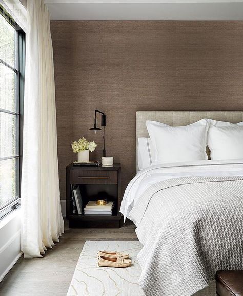 Packed with style, this modern gray and brown bedroom features an accent wall covered in brown grasscloth and positioned behind a heather gray tufted headboard accenting a bed dressed in white and gray bedding complemented with a heather gray waffle blanket. Grey Brown Bedrooms, Grasscloth Wallpaper Bedroom, Brown Bedroom Walls, White And Brown Bedroom, Grey And Gold Bedroom, Brown Accent Wall, Grey And White Bedding, Feature Wall Bedroom, Dressed In White