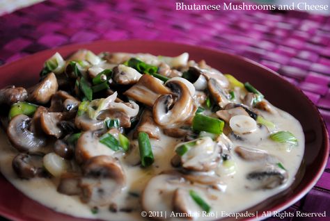 Shamu Datshi - In pan, place the sliced button mushrooms, 1/4 c water, 1T butter, & salt (if using) over high heat & bring to a boil. Reduce heat to medium-low, cover, & cook 5 minutes till the mushrooms cooked. Stir in 2/3 C (Amul) grated cheese, & 3/4 green onion, cover, and cook 2 minutes or until cheese melts. Pour into a serving dish and serve with rice. Ema Datshi, Bhutan Food, Mushroom And Cheese, Bhutan Travel, Thunder Dragon, Mushroom Recipe, Healthy Indian Recipes, Countries In The World, Dinner Themes