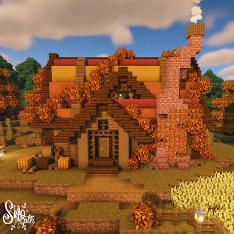 An autumn cottage in Minecraft. A warm chimney made of brick and granite on the front with smoke slowly emulating from the top. A red, orange, and yellow festive autumn roof shrouded in orange leaves and lined with dark oak. Cozy accents of window boxes, barrels, and pumpkins let you know this is your home for the autumn season. Pumpkin patches and small wheat crop fields frame either side of the house. Mincraft Fall House, Cute Fall Minecraft Houses, Minecraft Fall Cottage, Autumn Minecraft Aesthetic, Minecraft Halloween Banner Designs, Halloween Themed Minecraft House, Minecraft Fall Trees, Halloween Minecraft Village, Cute Halloween Minecraft Builds