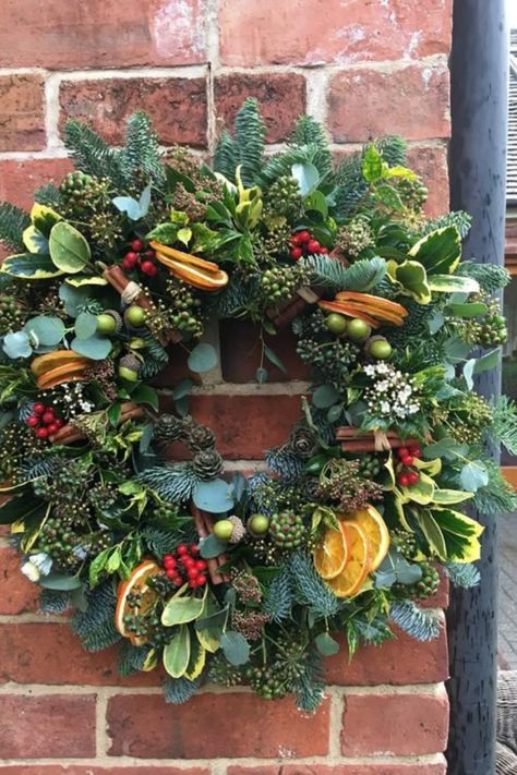 This wreath exudes a rustic charm, blending traditional winter greens with vibrant pops of dried orange slices. The wreath radiates warmth with its mix of pinecones, cinnamon sticks, and fresh berries, creating a festive atmosphere. Fresh Christmas Wreath, Christmas Wreath Ideas, Winter Greens, Christmas Wreaths With Lights, Orange Wreath, Holiday Wreaths Diy, Christmas Wreaths Ideas, Big Candles, Traditional Wreath