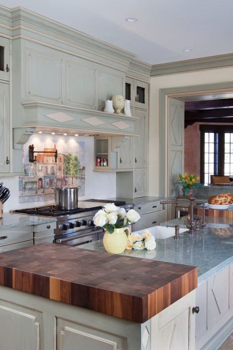 Cherry butcher block countertops flank the granite countertop on the island, providing ample prep space in this French country kitchen. The backsplash behind the stove features a hand-painted mural on porcelain and a traditional wall-mounted pot filler. Butcher Block And Granite Countertops, Organize Life, Organize Kitchen, Design Café, French Country Kitchens, Farmhouse Kitchen Island, Granite Countertop, Rustic Kitchen Design, New Kitchen Cabinets