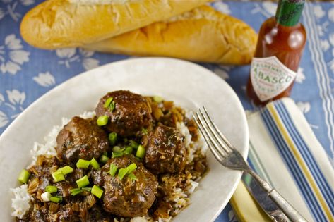 Classic homestyle recipe for highly-seasoned ground beef & pork meatballs first baked, then simmered in a dark roux gravy. Serve over rice & garnish with sliced green onions. This recipe makes a *lot*, but can be halved or the extra meatballs frozen. (*Note: Would skip browning meatballs in a skillet, & bake them no longer than 20 minutes. A few other steps could be streamlined as well.) #South #Southern Cajun Meatballs, South Louisiana Recipes, Meatball Stew Recipe, Meatball Stew, Meatballs And Gravy, Cajun Cooking, Louisiana Recipes, South Louisiana, Beef Short Ribs