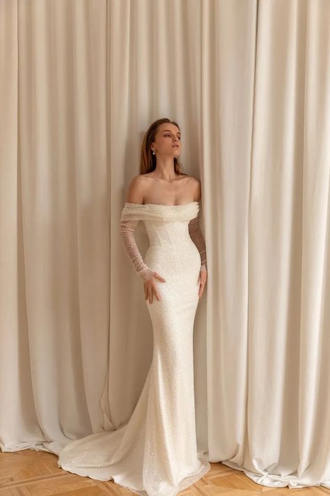 Points clés de la robe de mariée sirène avec paillette : 👗 Coupe sirène : épouse vos courbes pour une silhouette raffinée. 🥂 Bretelles audacieuses : placées sur le haut du biceps pour des épaules dénudées. 🌟 Manches longues : parfaites pour un mariage en demi-saison. ✨ Tissu pailleté : scintille à chaque mouvement, pour un effet féerique. 💃 Élégance et confort : idéale pour les mariées qui souhaitent allier style et aisance. La Robe de mariée Sirène Paillette est une véritable célébration de la féminité. Sa coupe sirène met parfaitement en valeur vos courbes, créant une silhouette sensuelle et sophistiquée. Conçue pour épouser votre corps avec élégance, elle vous offre une allure gracieuse et impeccable. Cette robe se distingue par ses bretelles positionnées sur le haut du biceps, une Off White Bride Dress, Theia Couture Wedding Dress, Loho Bride Dress, Long Sleeves White Dress, Form Fotting Wedding Dress, Wedding Ring Sleeve, Loft Wedding Dress, Cow Neck Back Wedding Dress, Wedding Dresses Romantic Sleeves