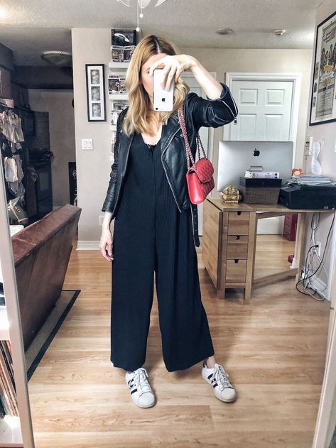 I am wearing a black oversized jumpsuit, a leather moto, Adidas Superstars, and a red purse. Jumpsuit And Converse Outfit, Wide Legged Jumpsuit Outfit, Black Jumpsuit Outfit Fall, Layered Jumpsuit Outfit, How To Style A Black Jumpsuit, Black Jumpsuit Outfit Winter, Black Jumpsuit Outfit Casual, Winter Jumpsuit Outfit, Wide Leg Jumpsuit Outfit