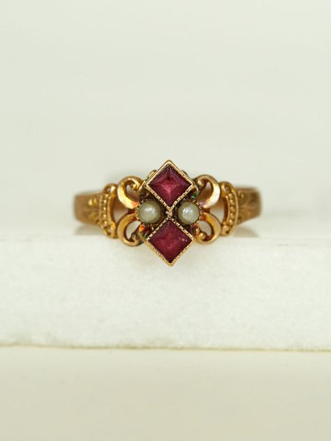 Her dainty Victorian style with gold work scrolls frame a powerful pair of Pearls and two stacked Rubies, set in a 10k gold band.  She's a fine addition to your collection.      	Ladies Size 6  	10k Yellow Gold Band  	Two Ruby red stones, pearls  	Arrives in gift box  Exclusively from Erin Pelicano Curated Vintage Collection. Each piece is intentionally chosen, pre owned, and ready to be loved and cherished again. sold as shown.  Shop the Curated Vintage Collection Dainty Vintage Jewelry, Victorian Rings Engagement, Pearl Jewelry Aesthetic, Victorian Wedding Ring, Vintage Ruby Ring, Ruby Ring Designs, Vintage Gold Jewelry, Antique Ruby Ring, Cute Promise Rings