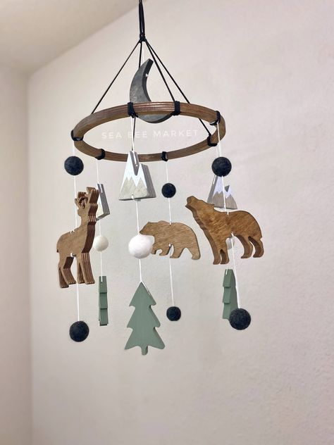 "This woodland crib mobile is one of my favorite designs. The mobile has everything to perfectly tie together your modern winter woodland, adventure, national park, or camping themed nursery.  The mobile comes complete with a few  snow capped mountains, one wolf, one bear, one buck/deer, three pine trees, a black moon, and charcoal grey wool balls. The colors perfectly contrast each other and are warm and inviting! The hanger is black faux leather/suede cord to tie together the perfect woodland Grey And Black Nursery Ideas, Forest Green Crib Nursery, Log Cabin Nursery Ideas, Black Bear Nursery Theme, Forest Baby Boy Nursery, Nursery Ideas Outdoor Theme, Alaska Themed Nursery, Happy Camper Nursery, Wilderness Theme Nursery