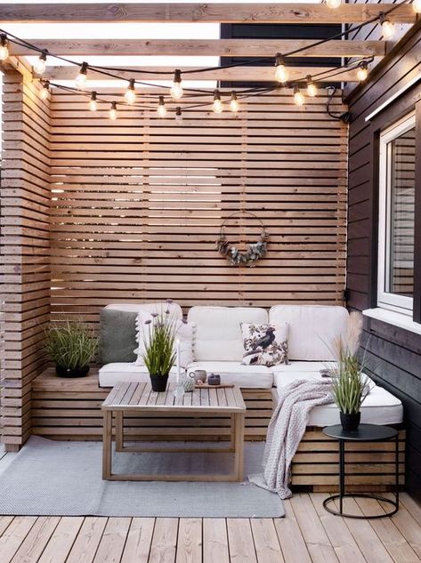 a small and cute patio with wood slat privacy screens and a bench, neutral cushions, a coffee table, string lights and potted greenery Patio Chico, Covered Patio Ideas, Small Patio Decor, Small Outdoor Patios, Christmas Patio, Patio Privacy, Patio Enclosures, Cozy Patio, Patio Shade