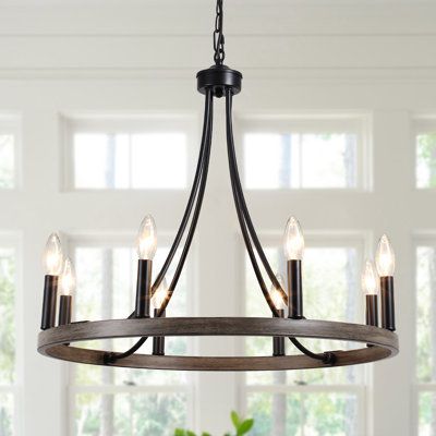 This rustic chandelier farmhouse presents a wagon wheel silhouette with 8 candle-style lamp holders perched atop in matte black and imitation wood grain, which cleverly reflect a sense of industrial farmhouse style. Finish: Imitation Wood-Look Metal Frame/Black | Farmhouse Chandelier 8 Lights Black, Gracie Oaks Wagon Wheel Chandelier, Dining Room Lights Fixture, Rustic Foyer Chandeliers | 19.6 H x 23.6 W x 23.6 D in | Wayfair Ski Chalet Chandelier, Chandeliers For Living Room Rustic, Kitchen Island With One Pendant Light, Wood And Black Chandelier, Rustic Farmhouse Chandelier, Farmhouse Wagon Wheel Chandelier, Living Room Lighting Ceiling Farmhouse, Modern Farmhouse Chandelier Living Room, Kitchen Lights Over Table