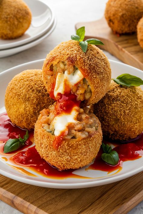 Golden-fried arancini filled with melted cheese, served on a plate with tomato sauce and garnished with fresh basil leaves. Homemade Arancini Balls, Risotto Balls Recipes, Luxury Food Recipes, Arancini Balls Recipes, Italian Food Authentic, Arancini Recipe Italian, Fried Risotto Balls, Italian Arancini, Rich Things