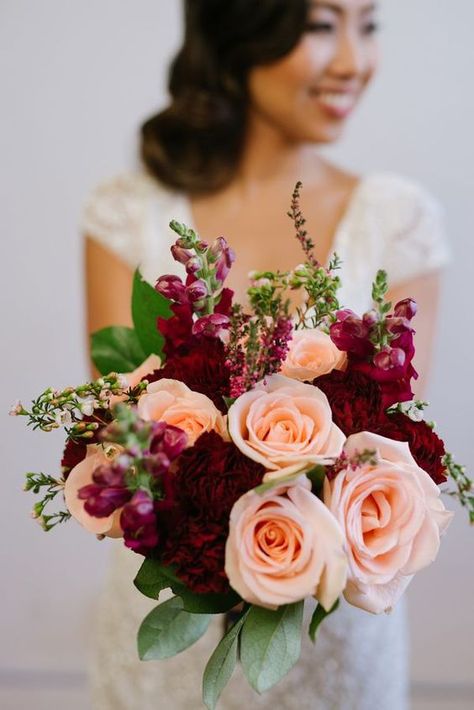 Burgundy and peach for burgundy wedding colors for 2025, burgundy bridesmaid dresses, white bridal gown, navy blue bridegroom suit and peach flower boutonniere, burgundy and peach flower and greenery bouquets, centerpieces and wedding cake décor, burgundy wedding napkins. Peach Floral Arrangements, Wedding Colors 2025, Boutonniere Burgundy, Bridesmaid Dresses Burgundy, Greenery Bouquets, Bridesmaid Dresses White, Burgundy Wedding Colors, Peach Bridesmaid Dresses, Peach Wedding Flowers