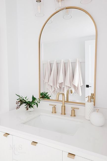 Vancouver bathroom renovation by Love Sims Home  Gold arched mirror, gold hardware and faucet, soft pink towels on hooks Small Bathroom Gold Hardware, Arch Gold Mirror Bathroom, Burlington Gold Bathroom, Large Gold Mirror Bathroom, Bathroom Remodel Gold Hardware, Gold Mirror For Bathroom, Gold Mirror In Bathroom, Gold Accent Powder Room, Arch Mirror Powder Room