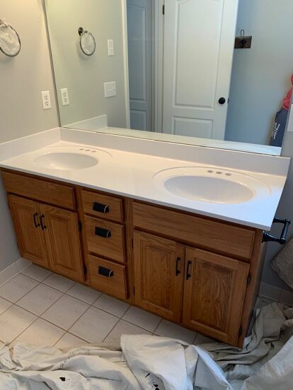 My builder grade Master Bathroom vanity was bad. Really bad. After two years I finally decided to do something about it and got to work. Here’s a before photo of the bathroom. Break Out the Spray Cans I used a can of Rustoleum Matte Black spray paint I had in the basement on the light fixture for a quick, easy and free light refresh! Cover Everything! For the countertop I purchased a $4.00 can of Rustoleum Appliance Epoxy spray paint from Walmart. I heard it produced lots of overs… Spray Paint Light Fixture Black, Rustoleum Appliance Epoxy Spray On Countertops, Epoxy Spray Paint Countertop, Master Bath Black Vanity, Rustoleum Appliance Epoxy, Bathrooms With Black Vanities, Bathroom Black Cabinets, Black Bathroom Cabinet, Master Bath Vanity Lighting