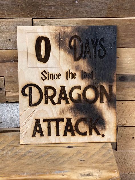 "It's only been zero days since last dragon attack! This wall sign would look perfect in any game room. Your companions should know that dragon attacks are a real thing to look out for... especially on game night! Burned edges and claw marks give it a little authentic feel. Your workplace sign will be 10x12\". Stay aware of workplace dangers! *each sign will be slightly different. Scratches and burn marks are random dragon markings." Nerdy Basement Ideas, Dnd Decorations Diy, Dnd Gift Ideas Diy, D&d Room Decor, Dnd Game Room Ideas, Nerd Decor Home, Dragon Halloween Decorations, Dungeon Room Ideas, Dnd Home Decor